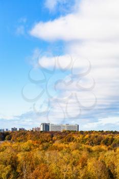 cloud front in blue sky over yellow forest and city in sunny autumn day