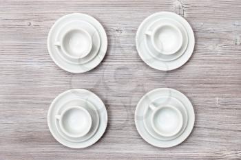 food concept - top view of four white cups and saucers on gray brown table