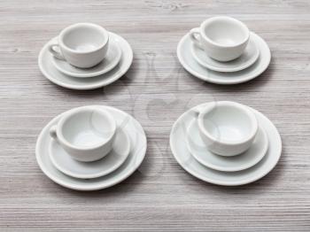 food concept - four white cups and saucers on gray brown table