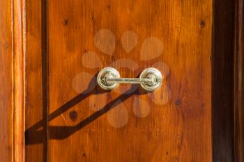travel to Italy - old external brass door handle on brown wooden door in Rome city