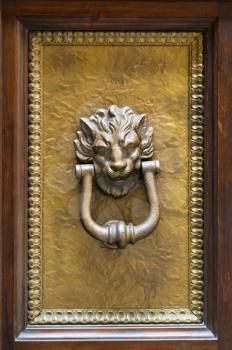 travel to Italy - lion head knocker on brass panel of old wooden door in Florence city