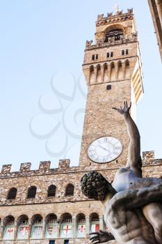 travel to Italy - statue The Rape of the Sabine Women close up and Palazzo Vecchio on Piazza della Signoria in Florence city.