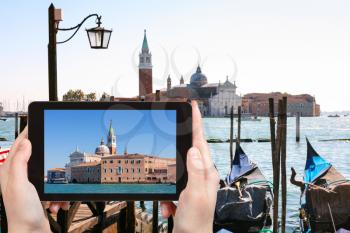 travel concept - tourist photographs San Giorgio Maggiore in Venice city on tablet in Italy
