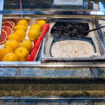 self-service buffet with cold breakfast - oatmeal, dried plums, orange fuits