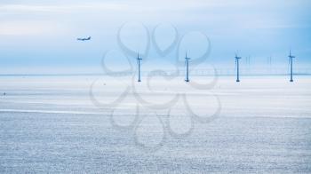 Travel to Denmark - view of airplane, bridge and offshore wind farm Middelgrunden in Oresund near Copenhagen city in Baltic Sea in blue autumn morning