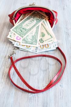 us dollars fall out from red leather handbag on wooden table