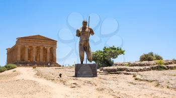AGRIGENTO, ITALY - JUNE 29, 2011: statue and Temple of Concordia in Valley of the Temples in Sicily. This area has largest and best-preserved ancient Greek buildings outside of Greece itself