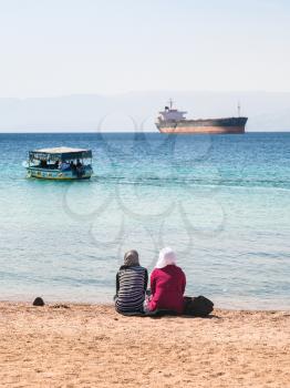 AQABA, JORDAN - FEBRUARY 23, 2012: arab women on urban beach in sunny winter day. Jordan country has only one exit to sea in Gulf of Aqaba, the length of the coast is 27 km