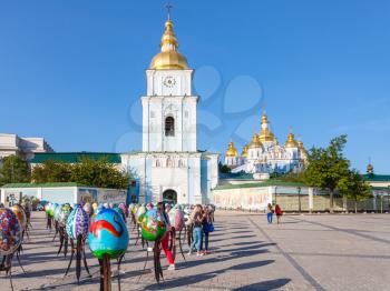 KIEV, UKRAINE - MAY 5, 2017: people and decorated Easter eggs on St Michael's Square and view of Saint Michael's Golden-Domed Monastery in Kiev city. The monastery was founded in 1108-1113