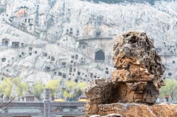 travel to China - old rock on East Hill and blurred West Hill of Chinese Buddhist monument Longmen Grottoes (Dragon's Gate Grottoes, Longmen Caves) in spring season