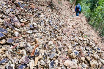 travel to China - tourist walks on path through landslide on mountain slope in Dazhai country of Longsheng Rice Terraces (Dragon's Backbone terrace, Longji Rice Terraces) in spring