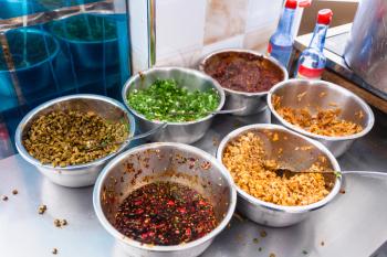 travel to China - dishes with seasonings, spices and toppings on kitchen table in urban chinese eatery in Longsheng town