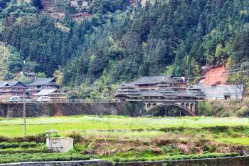 travel to China - view of Chengyang village with Bridge from fields in area of Sanjiang Dong Autonomous County in spring morning