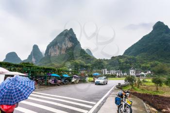 YANGSHUO, CHINA - MARCH 29, 2017: car and scooter parking lots near gate to village in Yangshuo county. Town is resort destination for domestic and foreign tourists because of scenic karst peaks