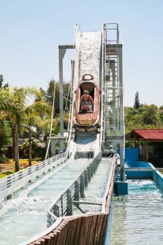 visitors in boat on water slide attraction in summer day