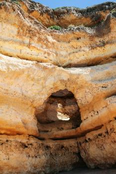 Travel to Algarve Portugal - cave in eroded sandstone rock on beach Praia Maria Luisa near Albufeira city in sunny day