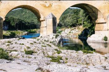 Travel to Provence, France - supports of ancient Roman aqueduct Pont du Gard in Gardon River near Vers-Pont-du-Gard town