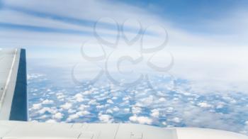 View from the airplane - wing of aircraft and above view of little clouds over land and sea in Greece in autumn