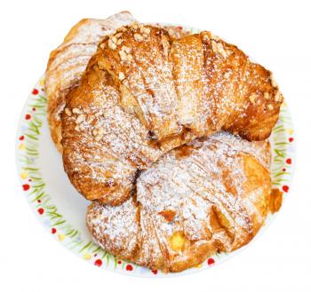 top view of three fresh italian croissants filled by vanilla and chocolate on plate isolated on white background