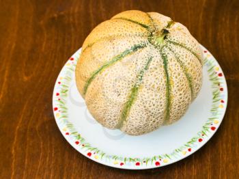 whole sicilian muskmelon (cantaloupe melon) on plate on wooden table