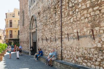 TAORMINA, ITALY - JUNE 29, 2017: visitors near wall of Duomo di Taormina (Cathedral San Nicolo di Bari) in city. Taormina is resort town on Ionian Sea in Sicily