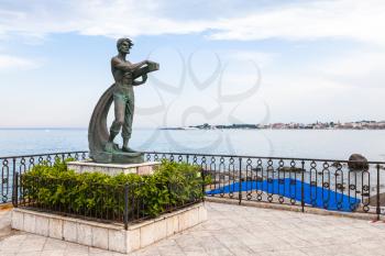 GIARDINI NAXOS, ITALY - JUNE 28, 2017: statue L' Uomo e il Mare (Man and the Sea) on waterfront in Giardini-Naxos. Giardini Naxos is seaside resort on Ionian Sea coast since the 1970s