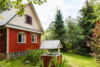 view of simple cottage and well from backyard in russian village in sunny summer day