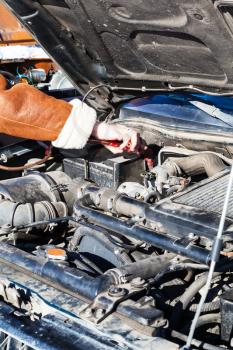 Jumpstart a dead car battery with another vehicle and jumper leads in cold winter day