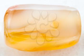 macro shooting of natural mineral rock specimen - bead from yellow Agate gemstone on white marble background