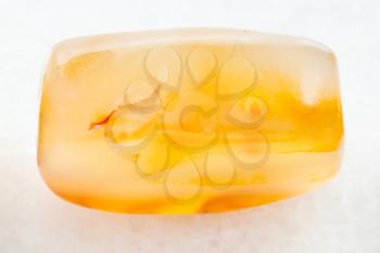 macro shooting of natural mineral rock specimen - cabochon from yellow Agate gemstone on white marble background