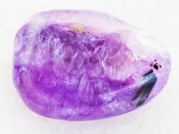 macro shooting of natural mineral rock specimen - polished Charoite gemstone on white marble background from Sakha Republic, Siberia, Russia