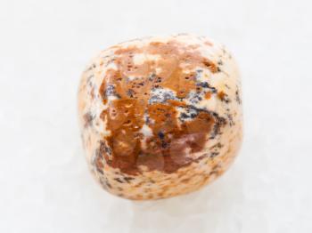macro shooting of natural mineral rock specimen - polished sandy Jasper gemstone on white marble background