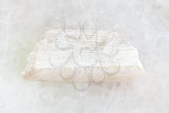 macro shooting of natural mineral rock specimen - raw Talc stone on white marble background