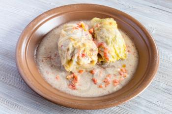 russian cuisine - stewed cabbage rolls on ceramic plate on gray wooden table