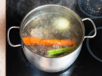 cooking soup - boiling meat stock in stockpot on ceramic cooker