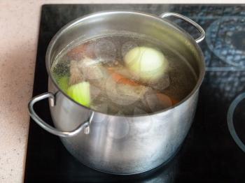 cooking soup - simmering meat broth in stockpot on ceramic cooker