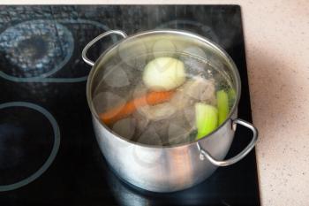 cooking soup - preparing meat broth in stockpot on ceramic cooker