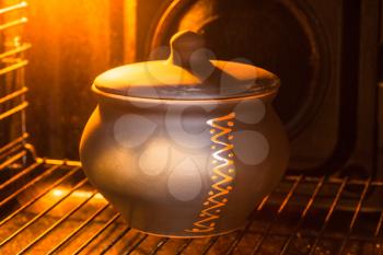 cooking soup - closed ceramic pot with stewed vegetables in hot electric oven
