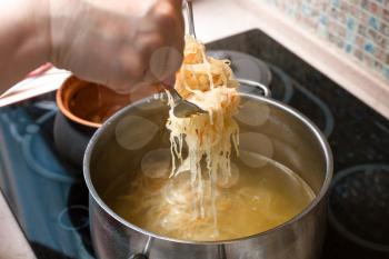 cooking soup - the cook transfer stewed sauerkraut from ceramic pot into saucepan with meat broth
