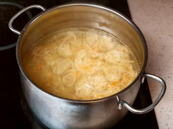cooking soup - cabbage soup with stewed sauerkraut in steel stockpot on ceramic cooker