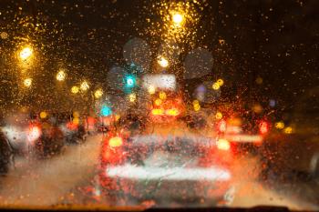 driving in night snowfall in Moscow - unfocused background with water from melting snow on the windshield in evening (focus on windscreen glass)