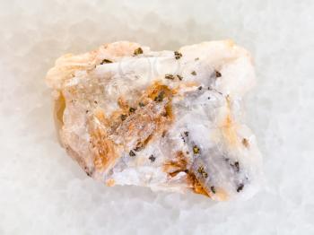 macro shooting of natural mineral rock specimen - native gold in raw quartz stone on white marble background