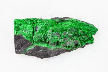 macro shooting of natural mineral stone specimen - green Uvarovite crystals on raw rock on white marble background from Saranovskoye mine, Ural Mountains, Russia