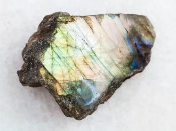 macro shooting of natural mineral rock specimen - polished piece of labradorite stone on white marble background from Finland