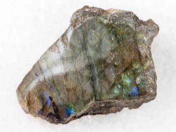 macro shooting of natural mineral rock specimen - tumbled slab of labradorite stone on white marble background from Finland