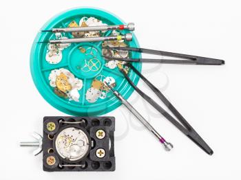 watchmaker workshop - top view of tools and spare parts for repairing watch on white background
