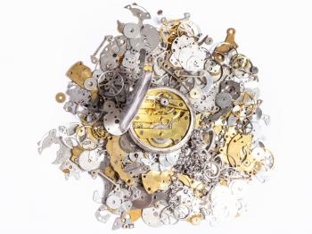 watchmaker workshop - top view of open silver pocket watch on pile of old clock spare parts on white background