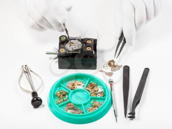 watchmaker workshop - above view of repairing old mechanical wristwatch on white table