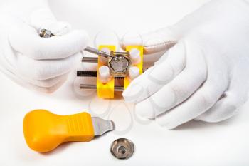 watchmaker workshop - cleaning battery place in quartz wristwatch by screwdriver on white background