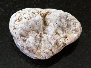 macro shooting of natural mineral rock specimen - pebble of white Granite stone on dark granite background